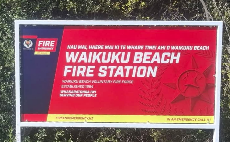 Waikuku Beach Fire Station sign, including the original Fire and Emergency New Zealand emblem and Māori and English lettering.